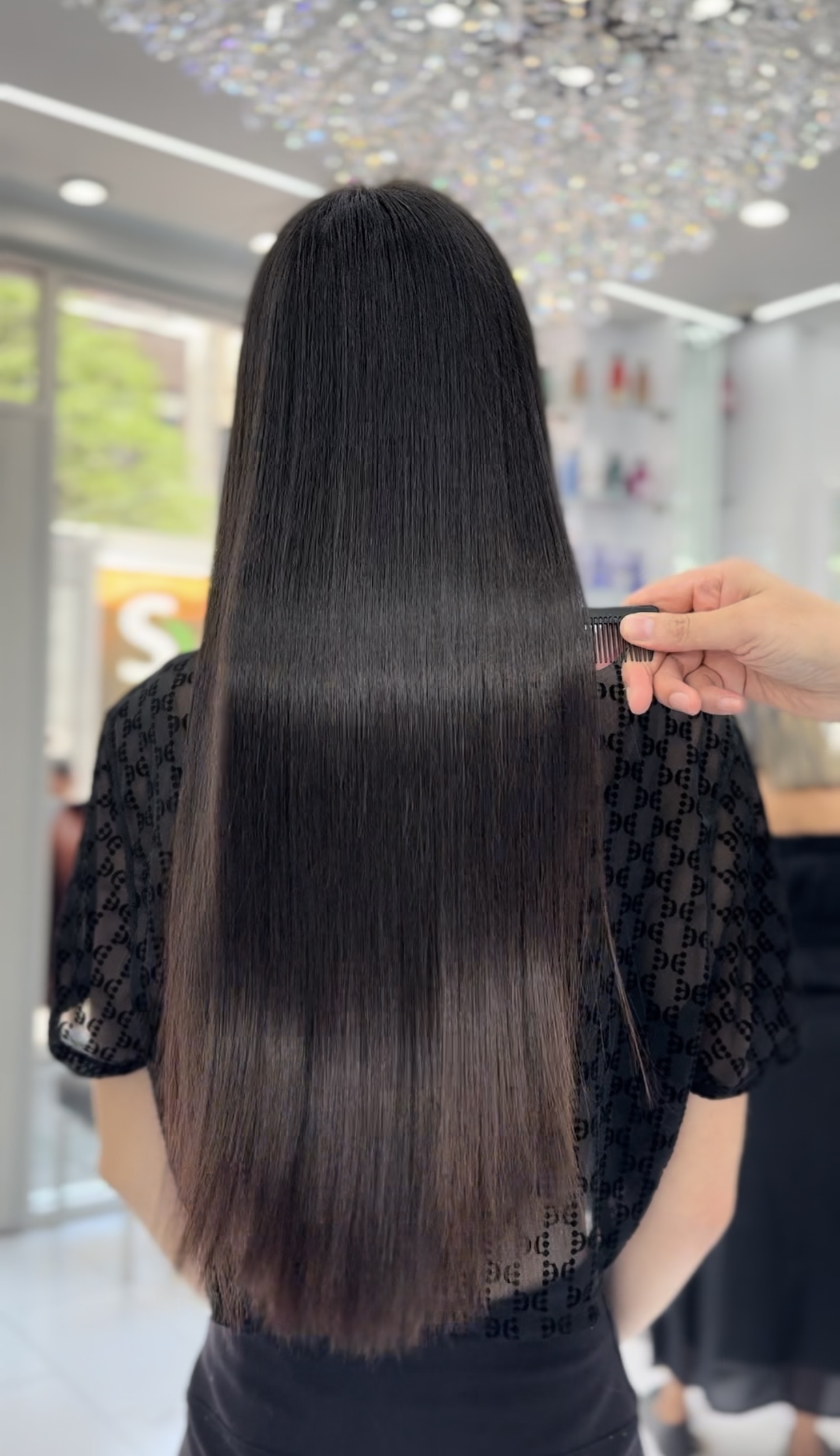 Long jet-black hair being combed smooth after a keratin treatment