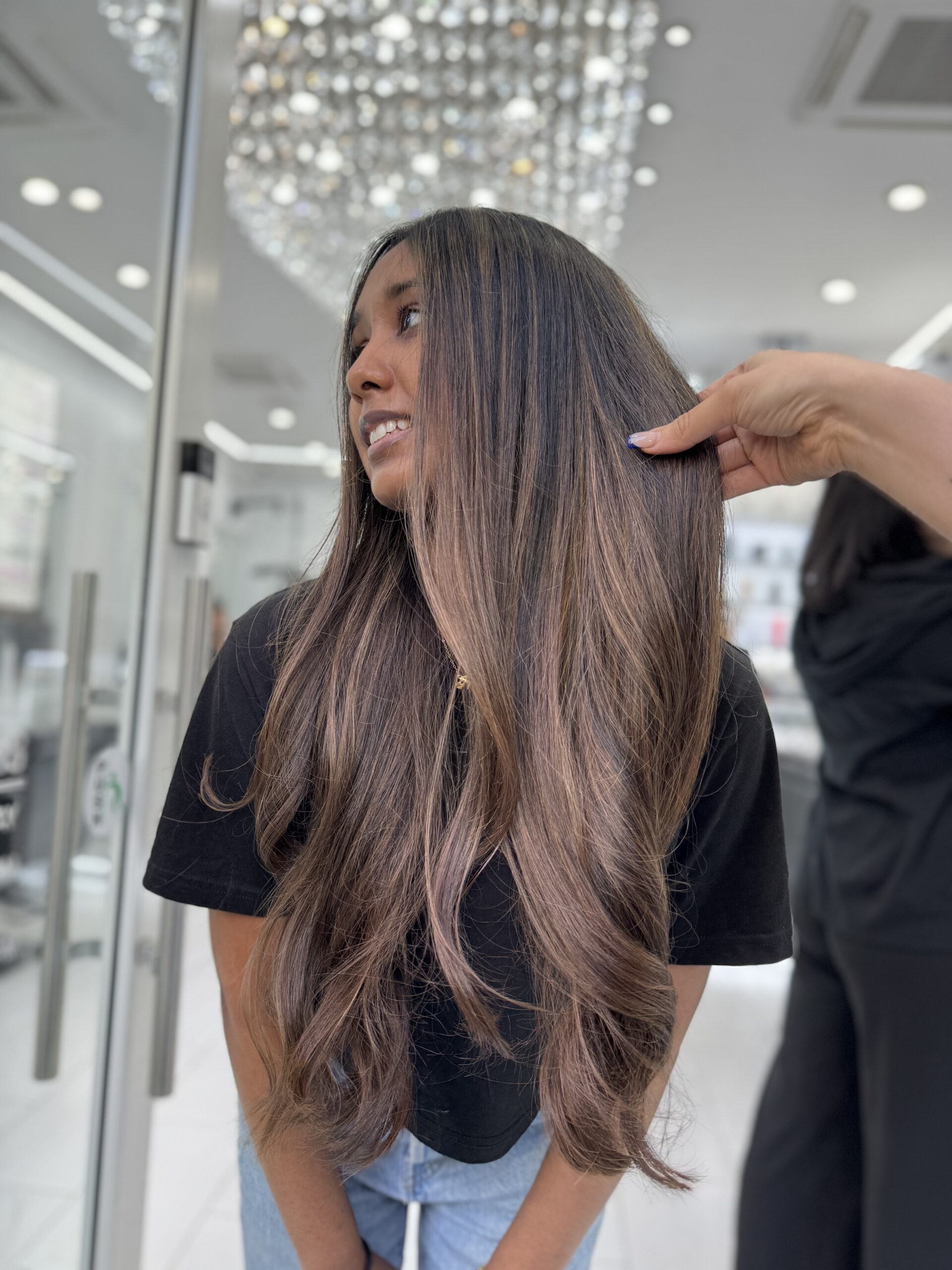 Long brown balayage being styled in the salon