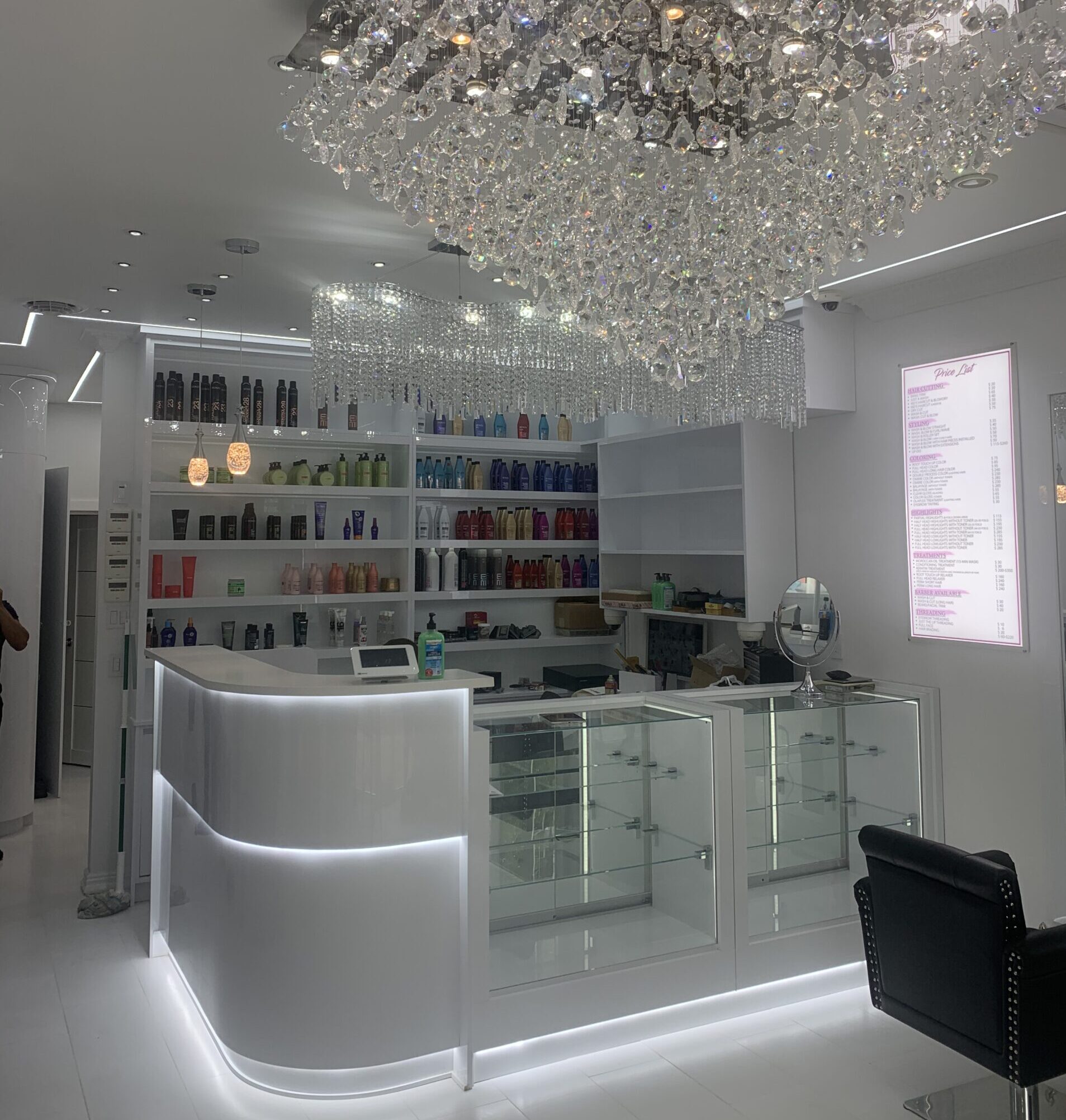 Salon reception desk with crystal chandelier and product shelves at 23rd Street Hair Salon
