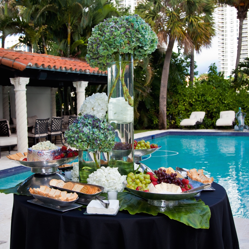 Elegant outdoor poolside catering table with floral centerpiece and platters