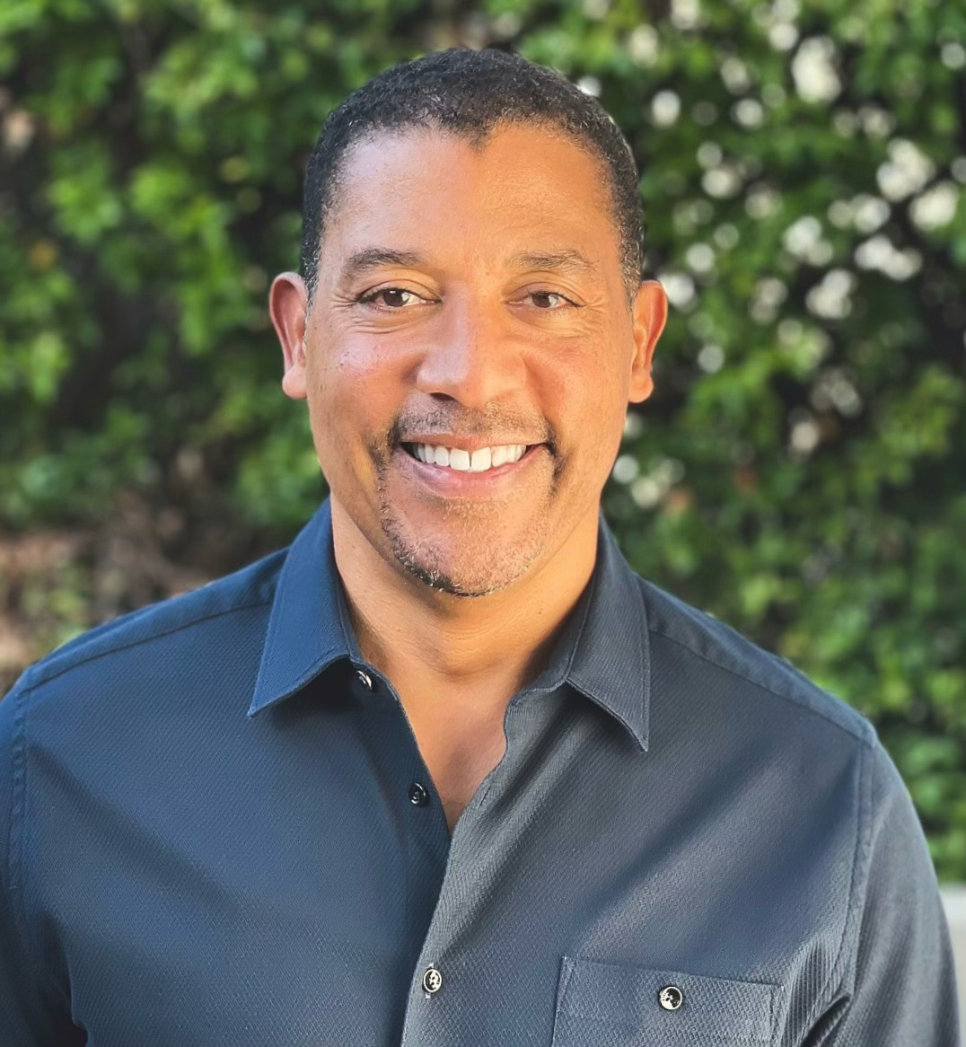 Headshot of David White, Founder and CEO of 3CG Ventures, smiling outdoors in front of green foliage
