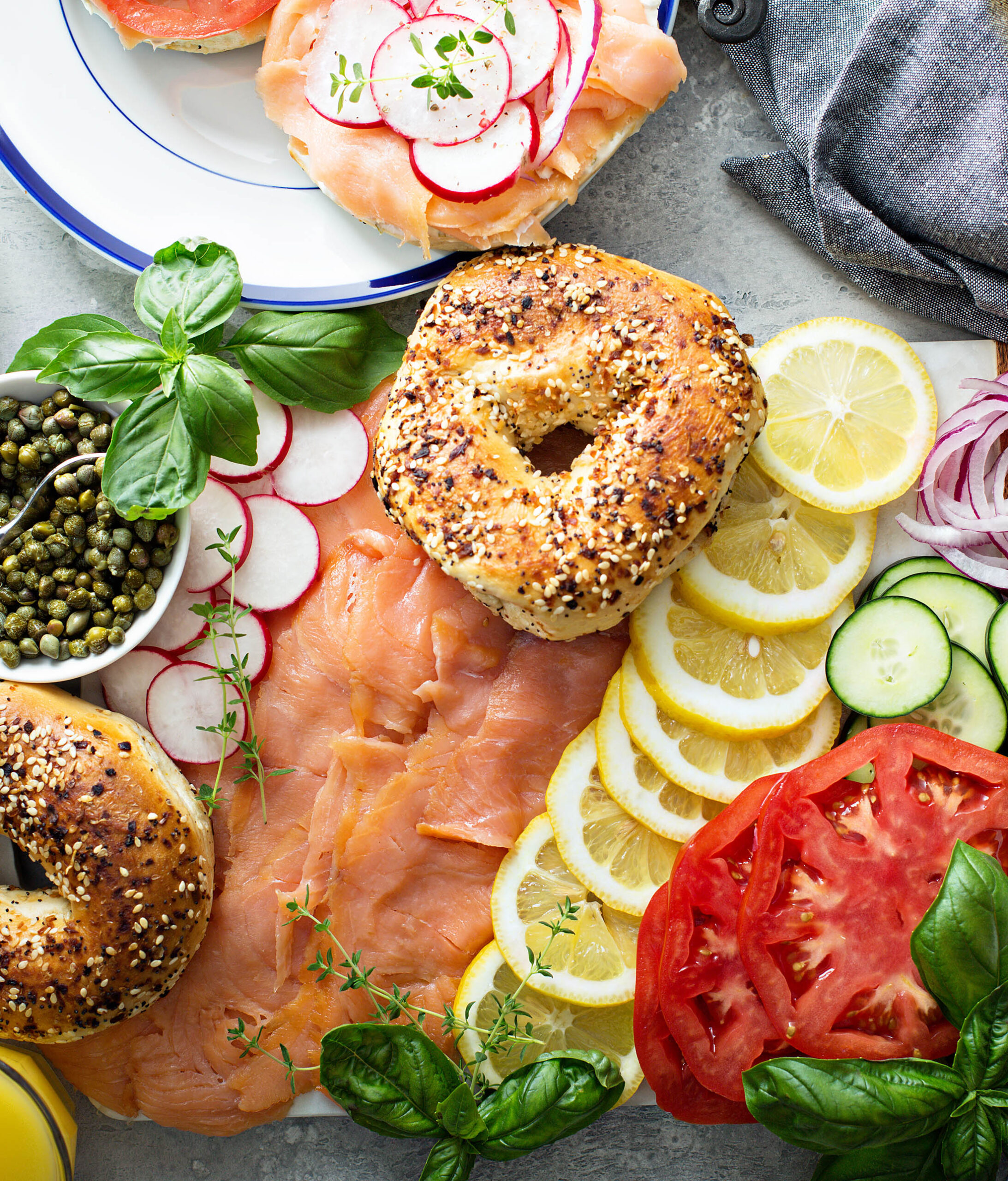 Overhead bagel and lox platter with smoked salmon, capers, radishes and lemon