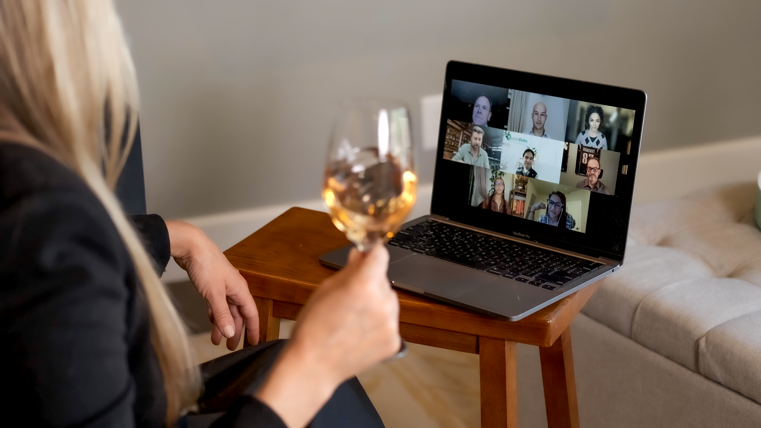 Woman with a glass of rosé hosting a multi-participant virtual wine tasting on a laptop
