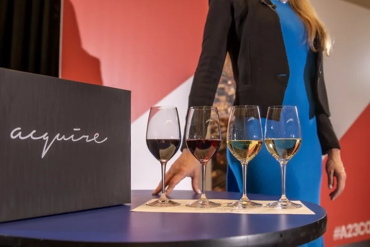 Wine glasses lined up beside an Acquire branded black box at a corporate in-person event