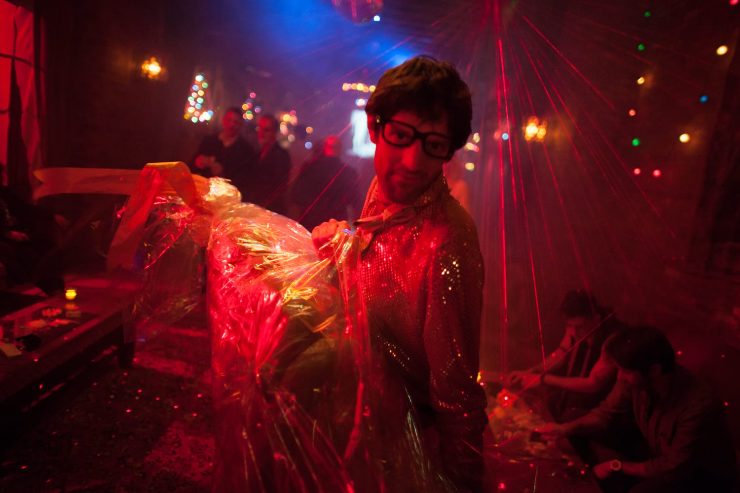 Man in a glittery jacket amid red lasers at Absolut AREA nightclub