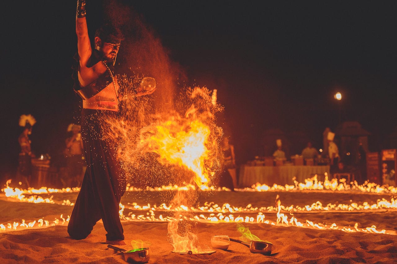 Fire performer creating a fireball on a beach at night