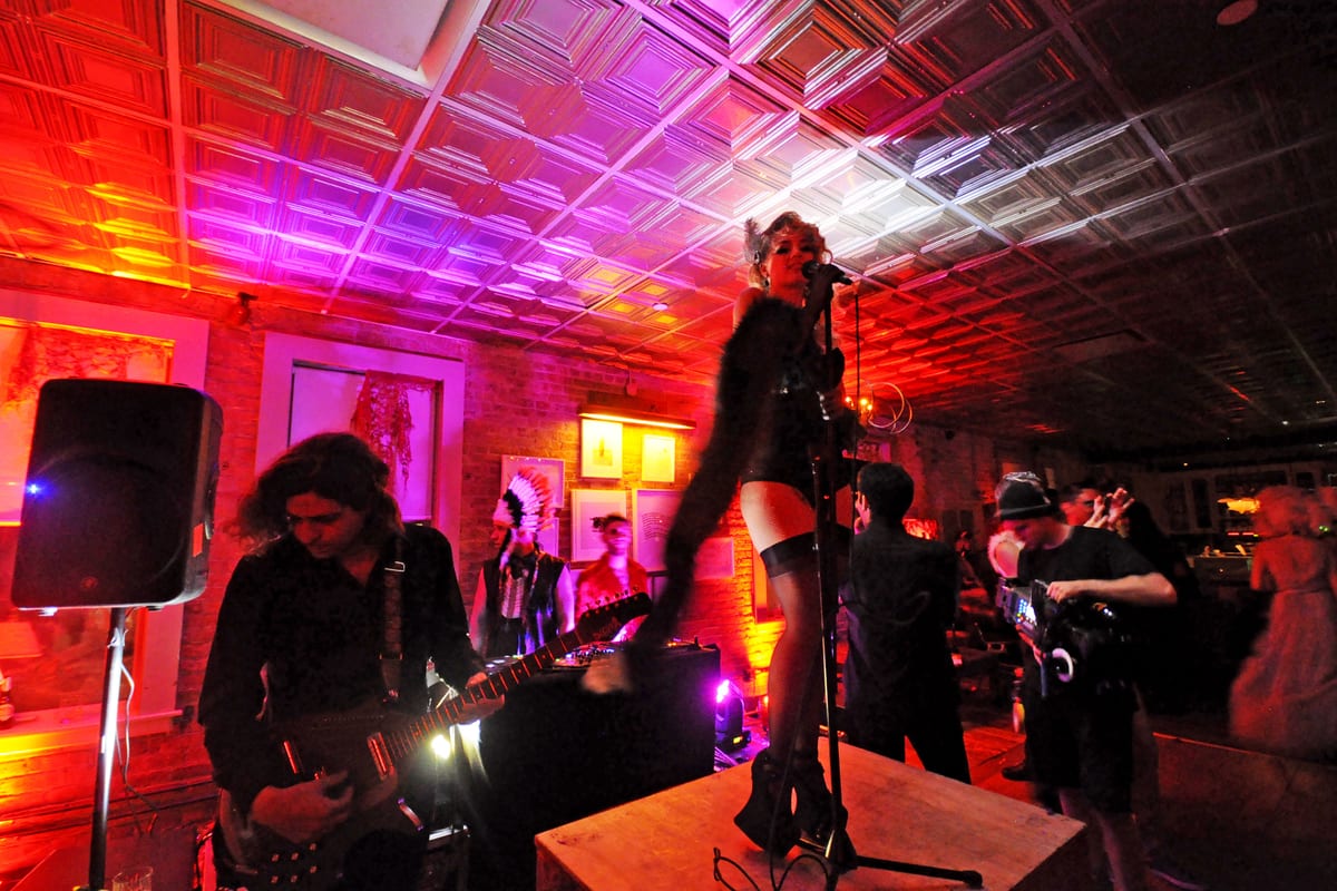 Singer on a tabletop under purple and red light at Soho House Halloween
