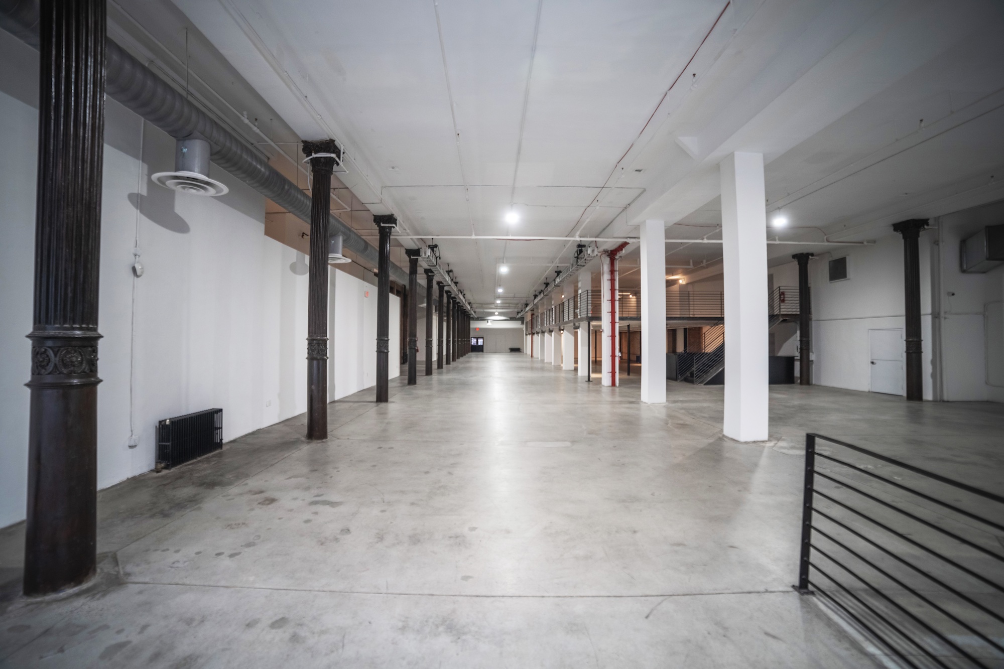 Iron23 long open event hall with ornate dark cast-iron columns, polished concrete floor and mezzanine level