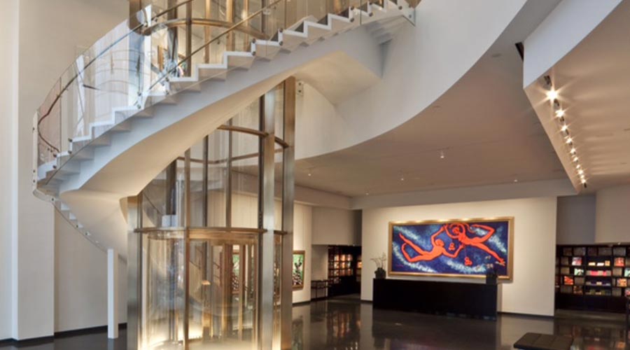 Upscale gallery lobby with curved staircase, glass elevator and large red figurative painting