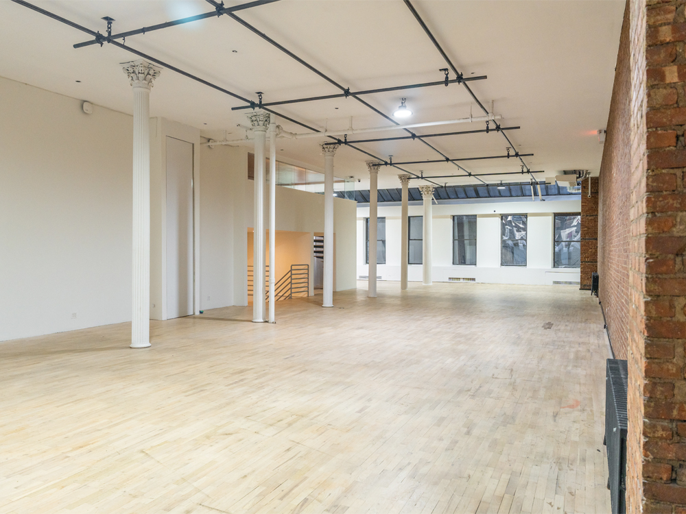 Event space with white Corinthian columns, track lighting and exposed brick set for a pop-up