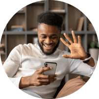 Smiling young man waving at his smartphone