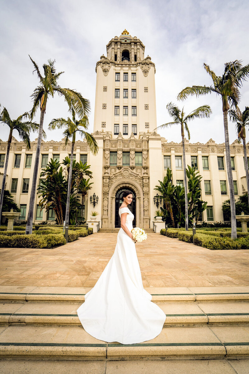 Bride in white gown with cathedral train at Beverly Hills City Hall, surrounded by palm trees
