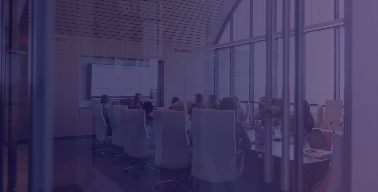 Leaders seated around a conference table watching a presentation