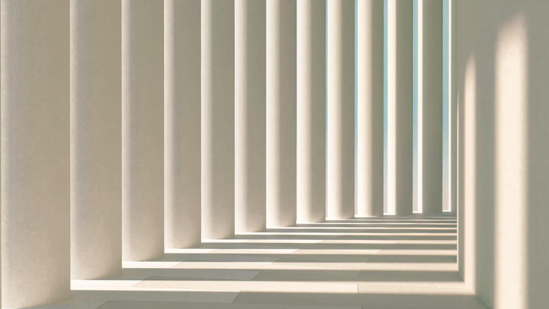 Corridor of tall white architectural columns casting dramatic shadows on a marble floor