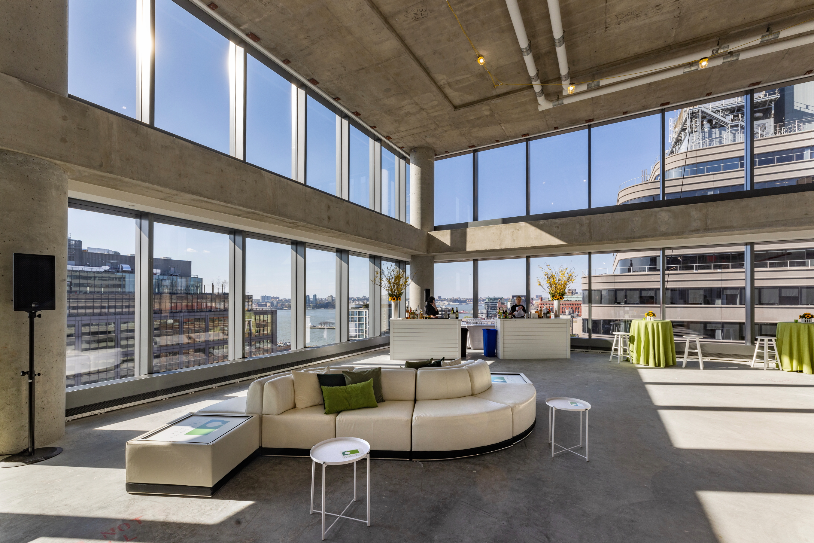 Loft-style event venue with river windows and a circular white sectional sofa
