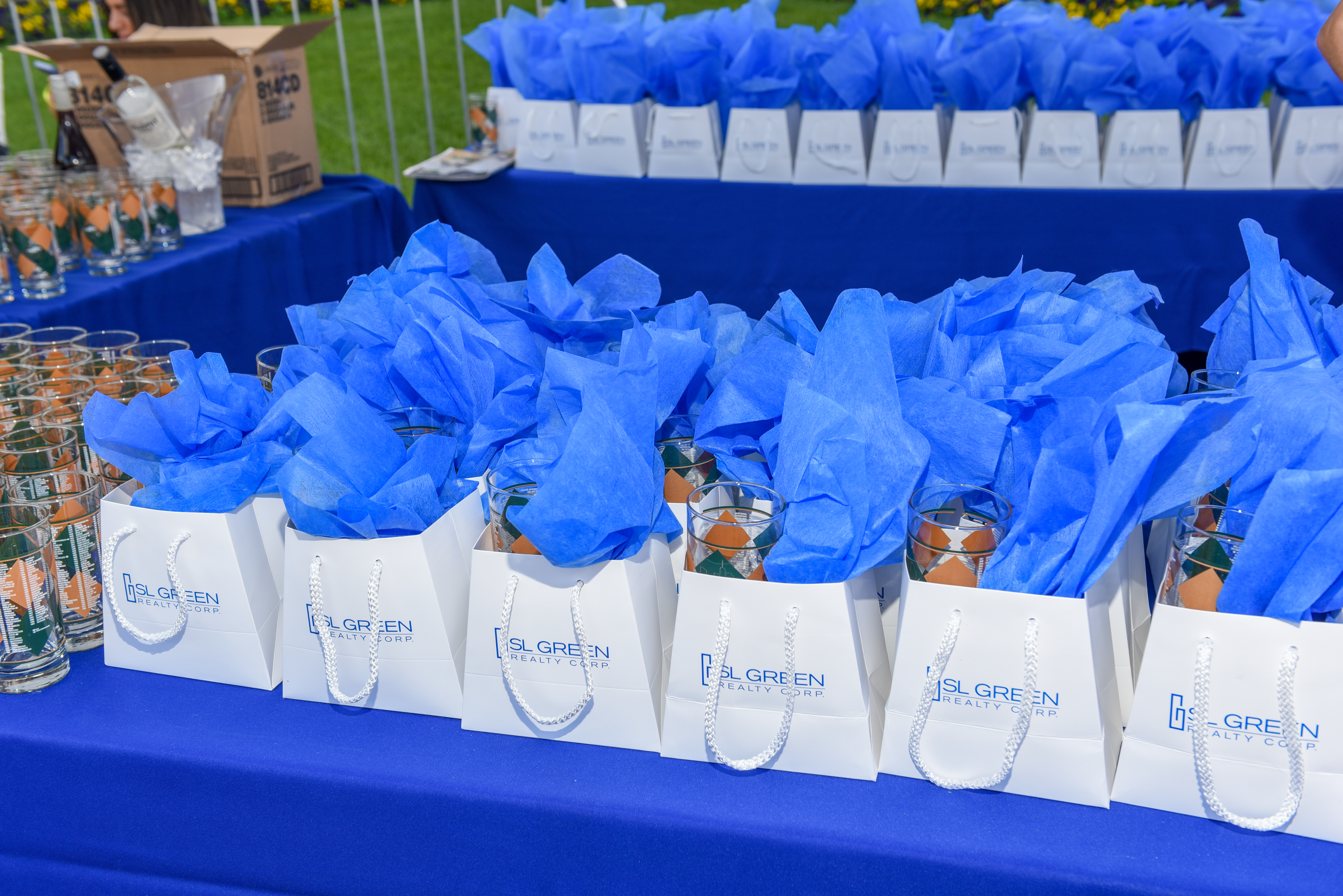 Branded SL Green Realty gift bags with blue tissue on a blue-draped event table