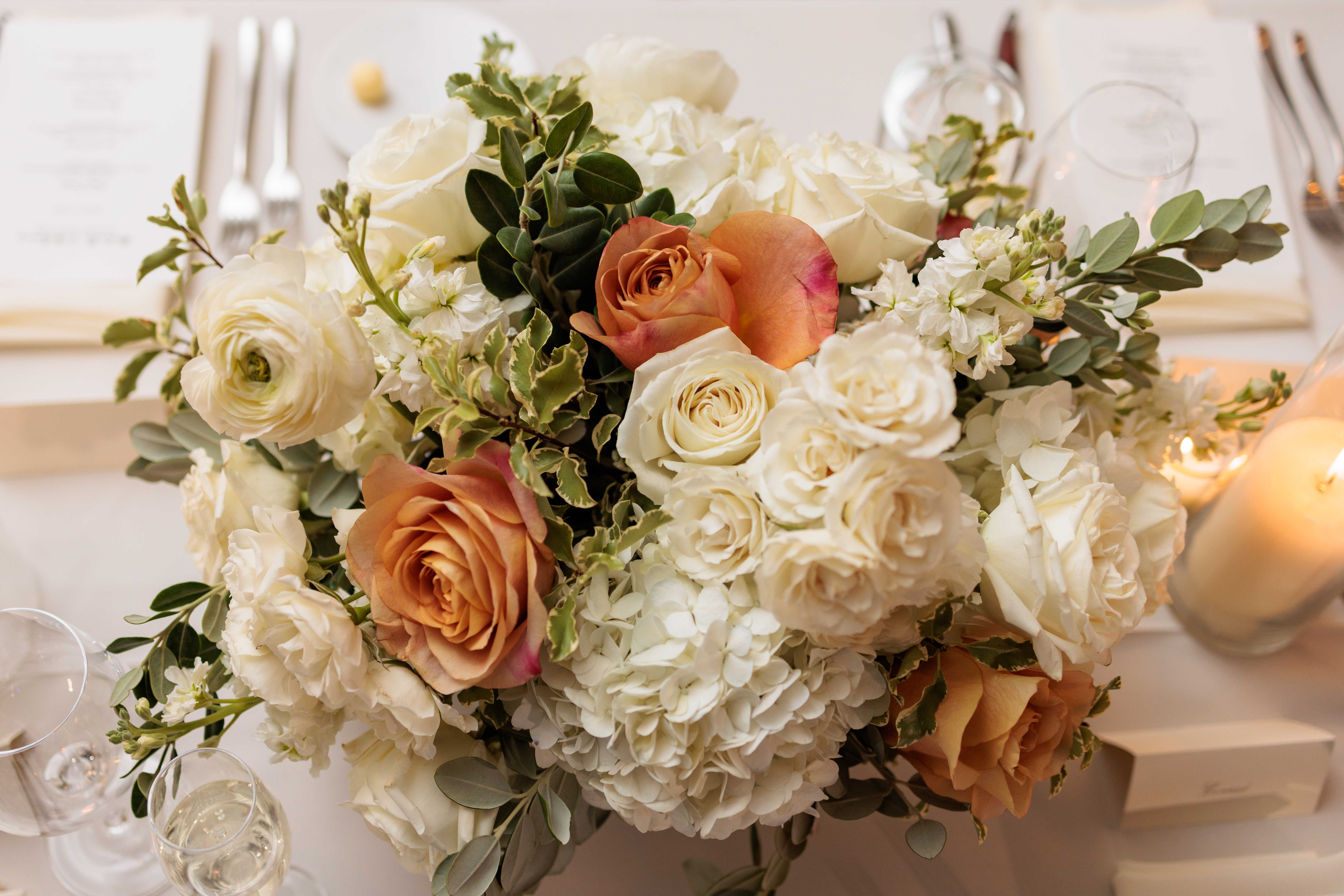 Floral centerpiece with white hydrangeas and cream roses on a set dinner table
