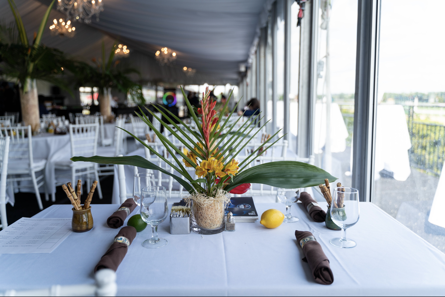 Tented event table with tropical florals overlooking a racetrack