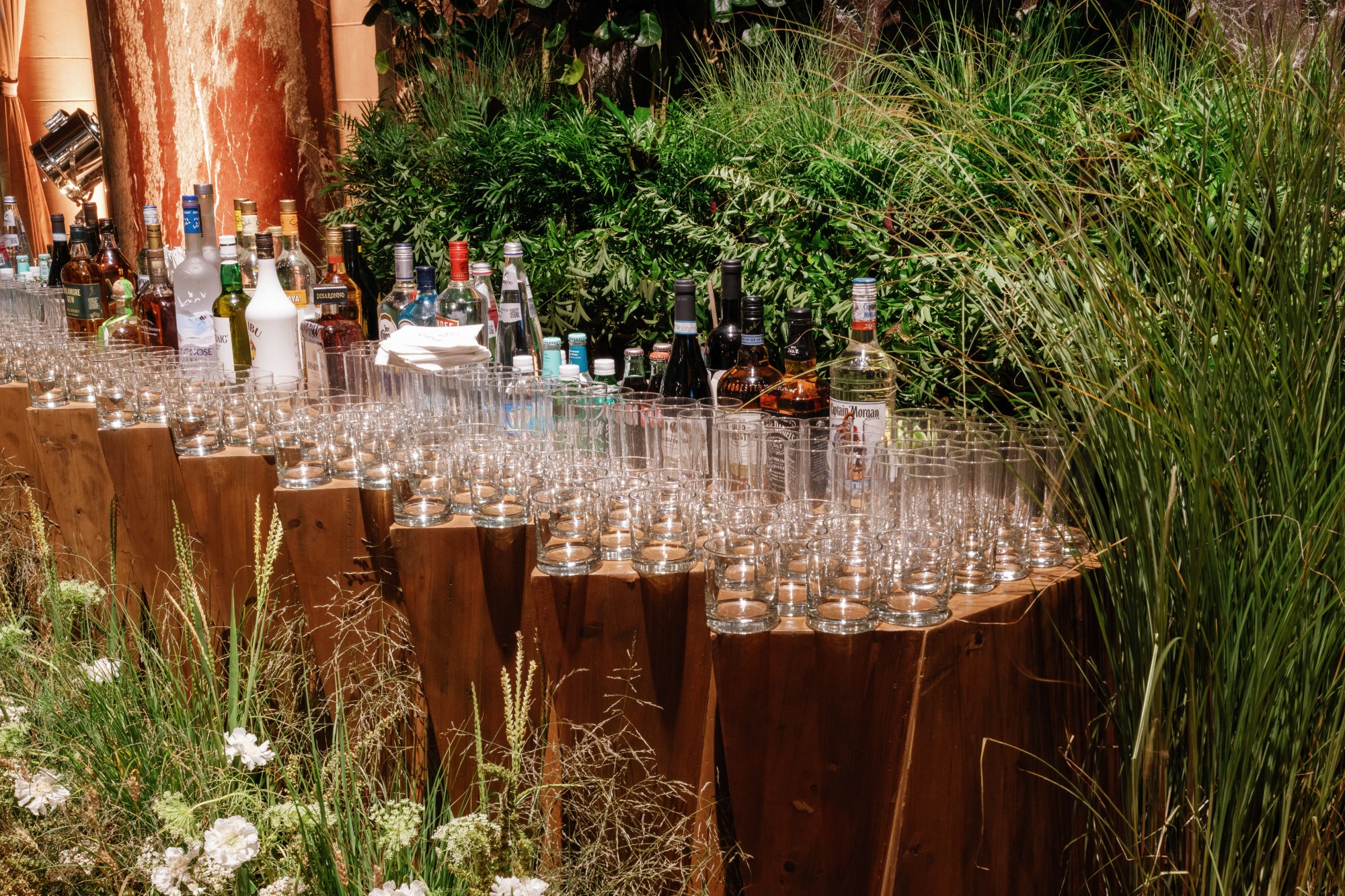 Rustic outdoor bar on wooden stump pedestals surrounded by greenery