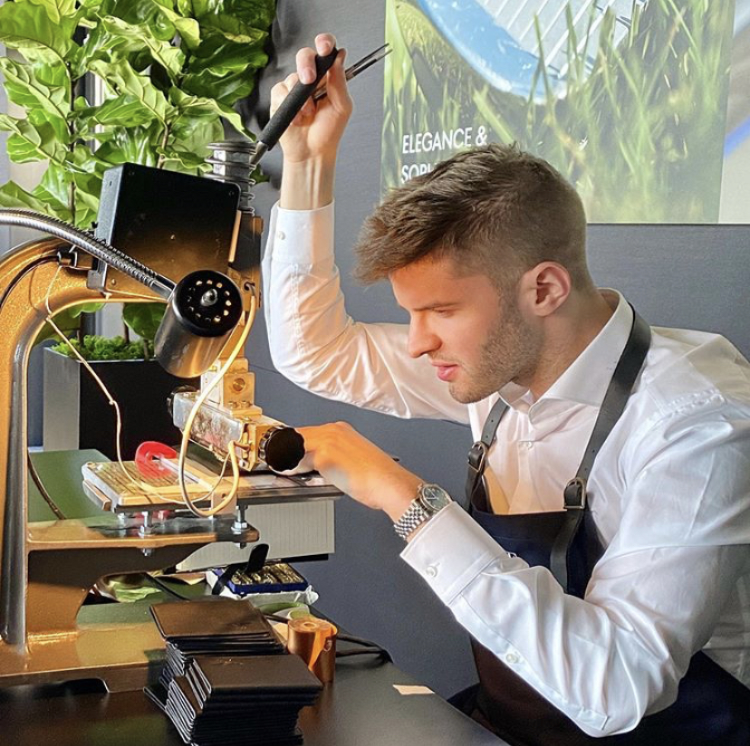 Young artisan in a leather apron engraving items at a workbench