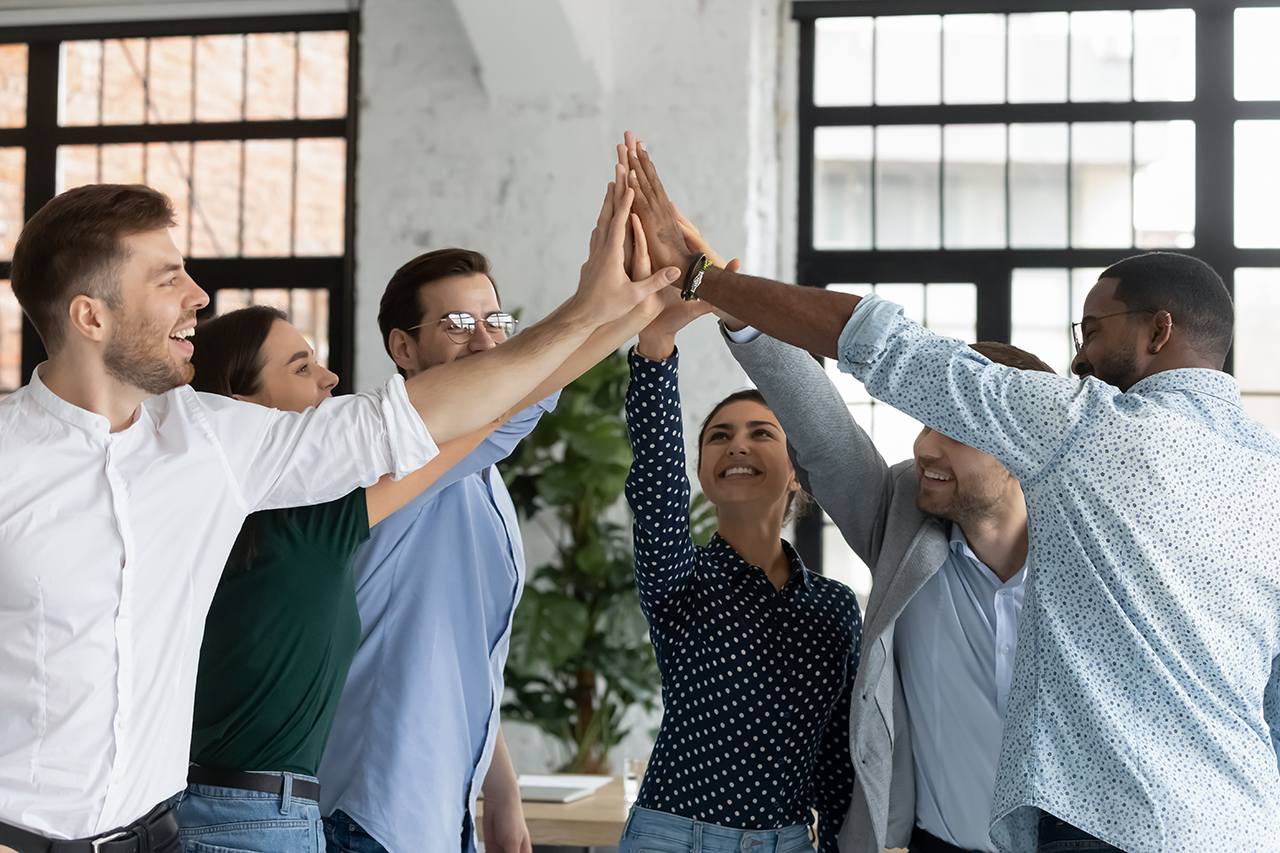 A diverse group of young office workers giving a group high-five