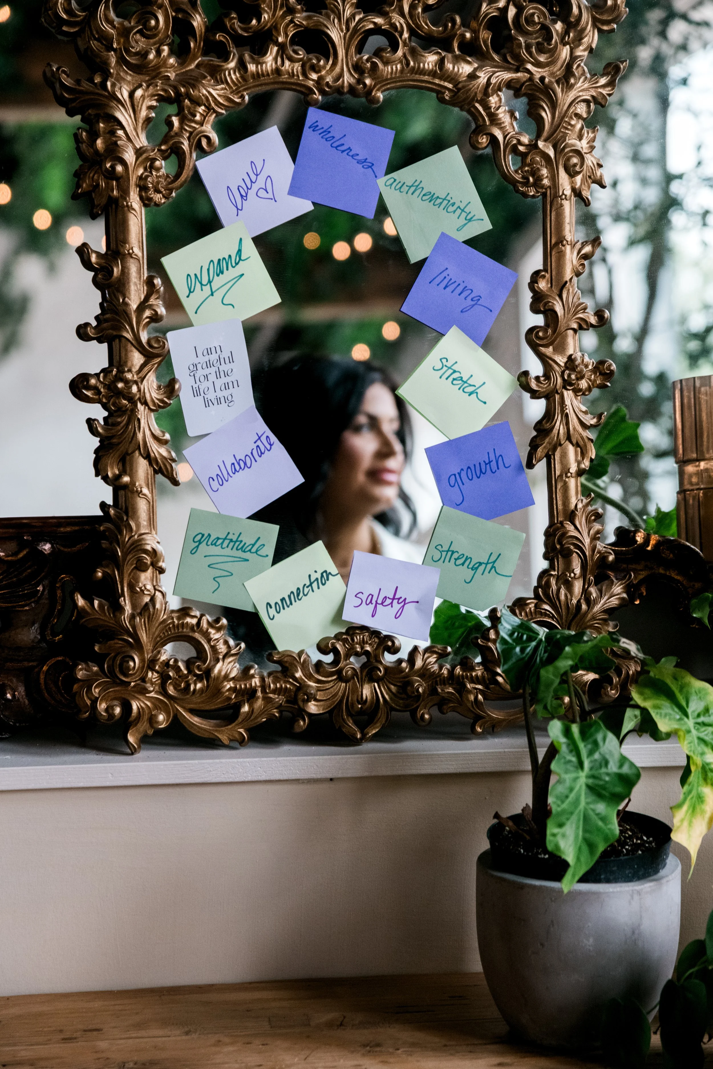 Ornate gold mirror covered with affirmation sticky notes reading love, gratitude and growth