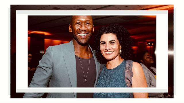 A man in a grey blazer and a woman in a blue dress smiling together at an event