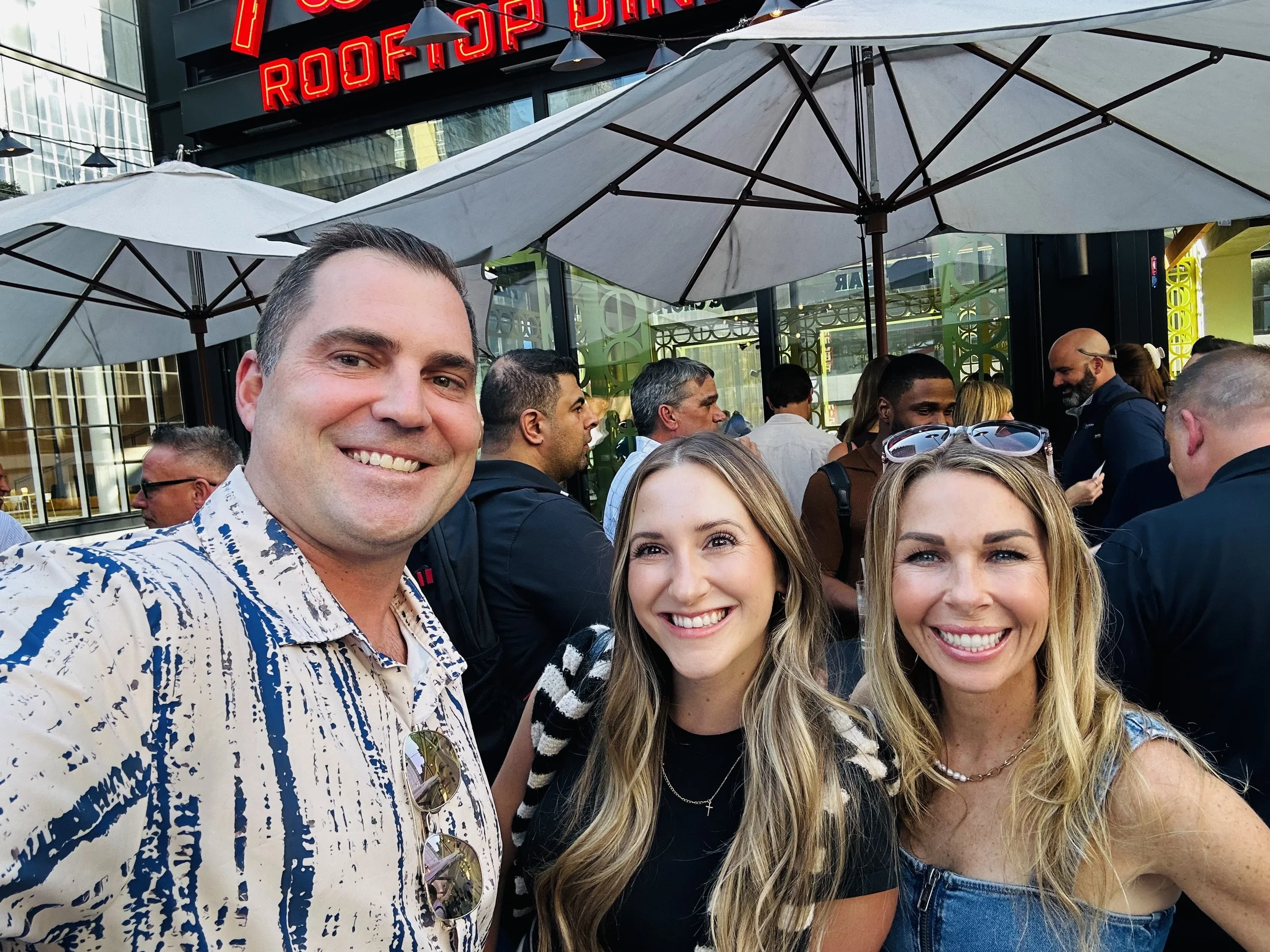 Three people at a rooftop dining venue with umbrellas