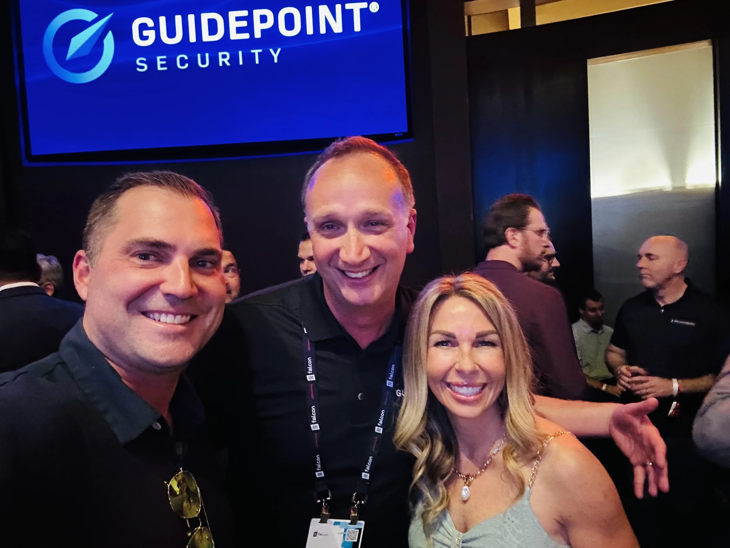 Three people in front of GuidePoint Security signage