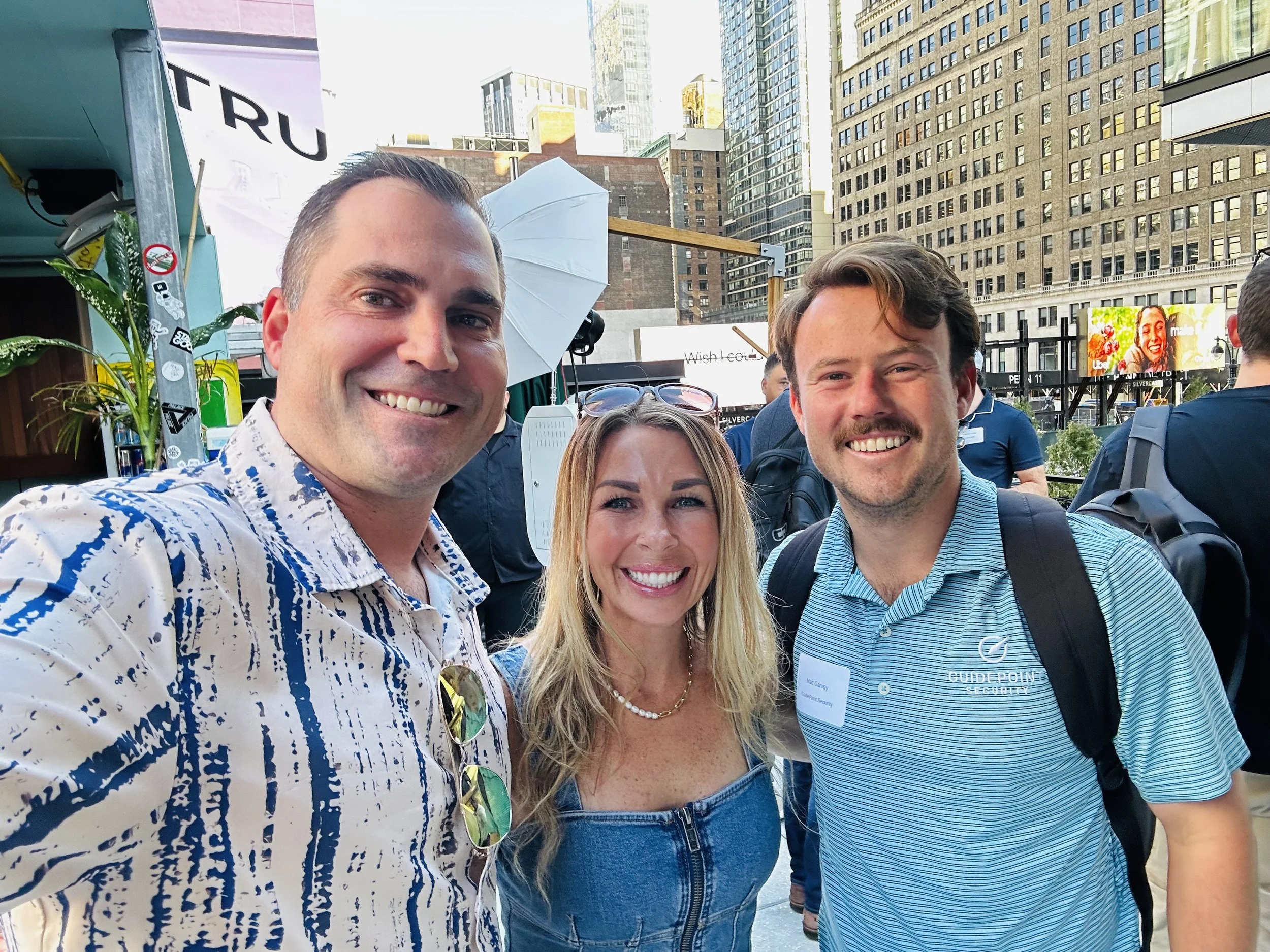 Three people on an NYC rooftop, one wearing a GuidePoint Security polo