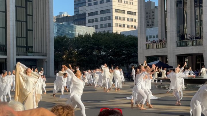 Dancers in white performing at Lincoln Center plaza at sunset