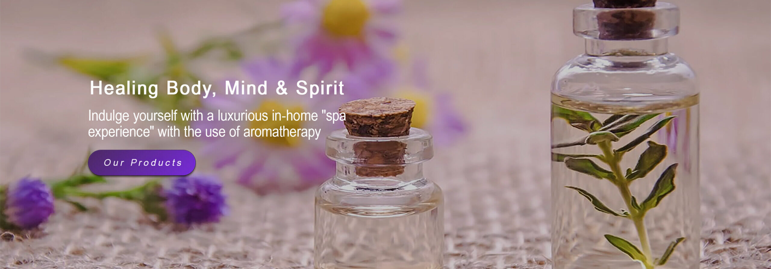Two corked glass bottles surrounded by soft purple flowers