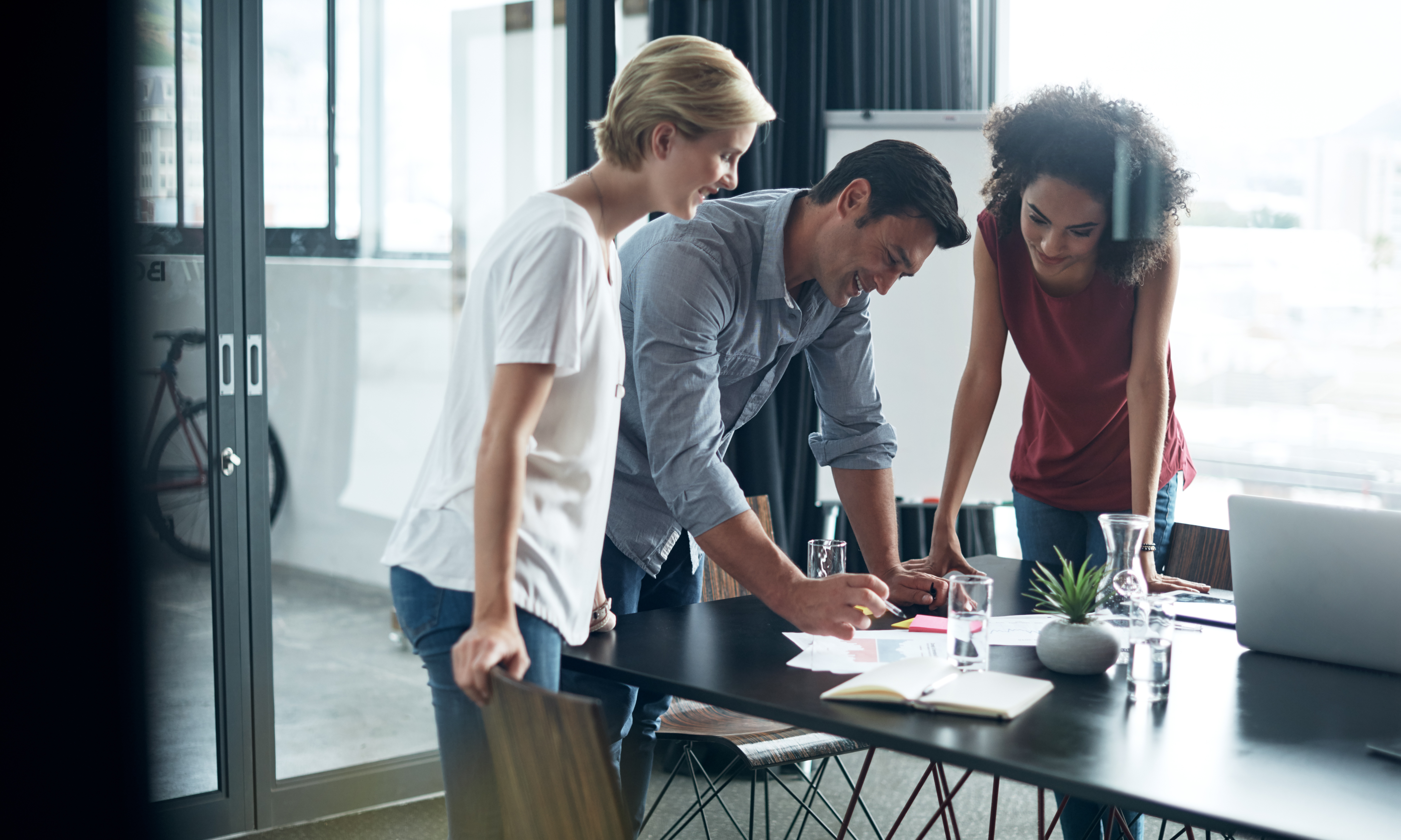 Three professionals collaborating around a conference table in a modern office