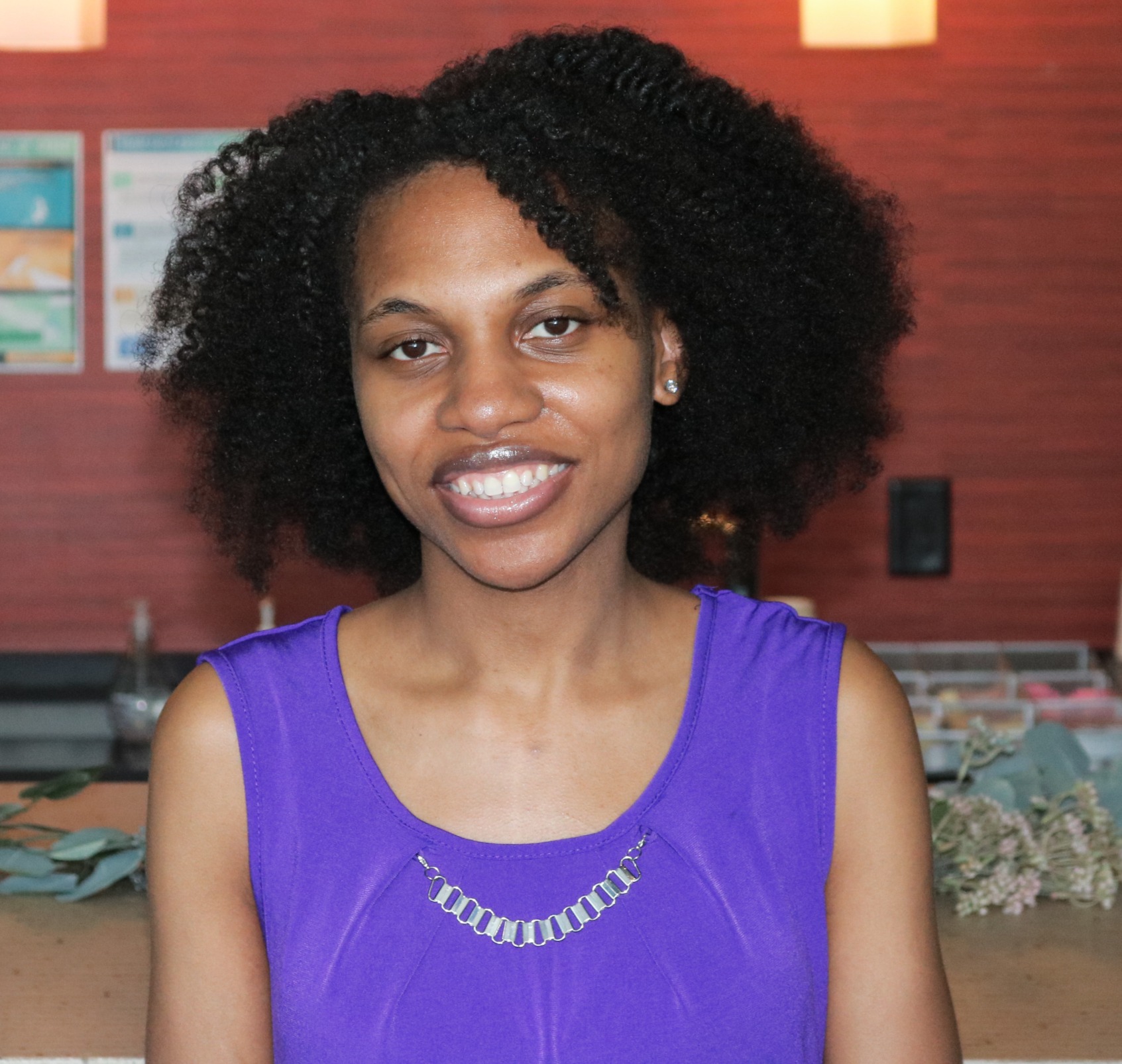 Dr. Lisa Battle-Gwathney in a purple sleeveless top, smiling, in front of a red brick wall.