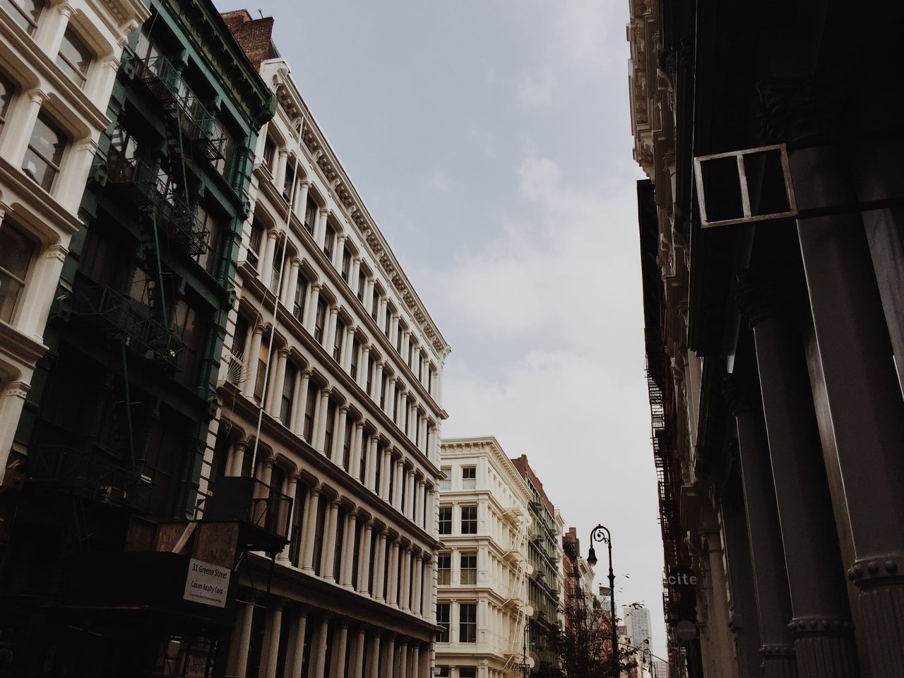 Low-angle view of SoHo cast-iron building facades on a New York City street under an overcast sky