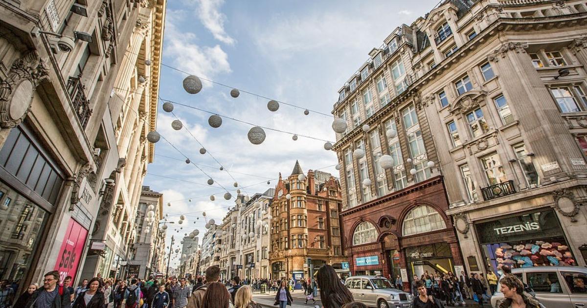 Busy retail high street with decorative globe lights strung overhead and crowds of shoppers