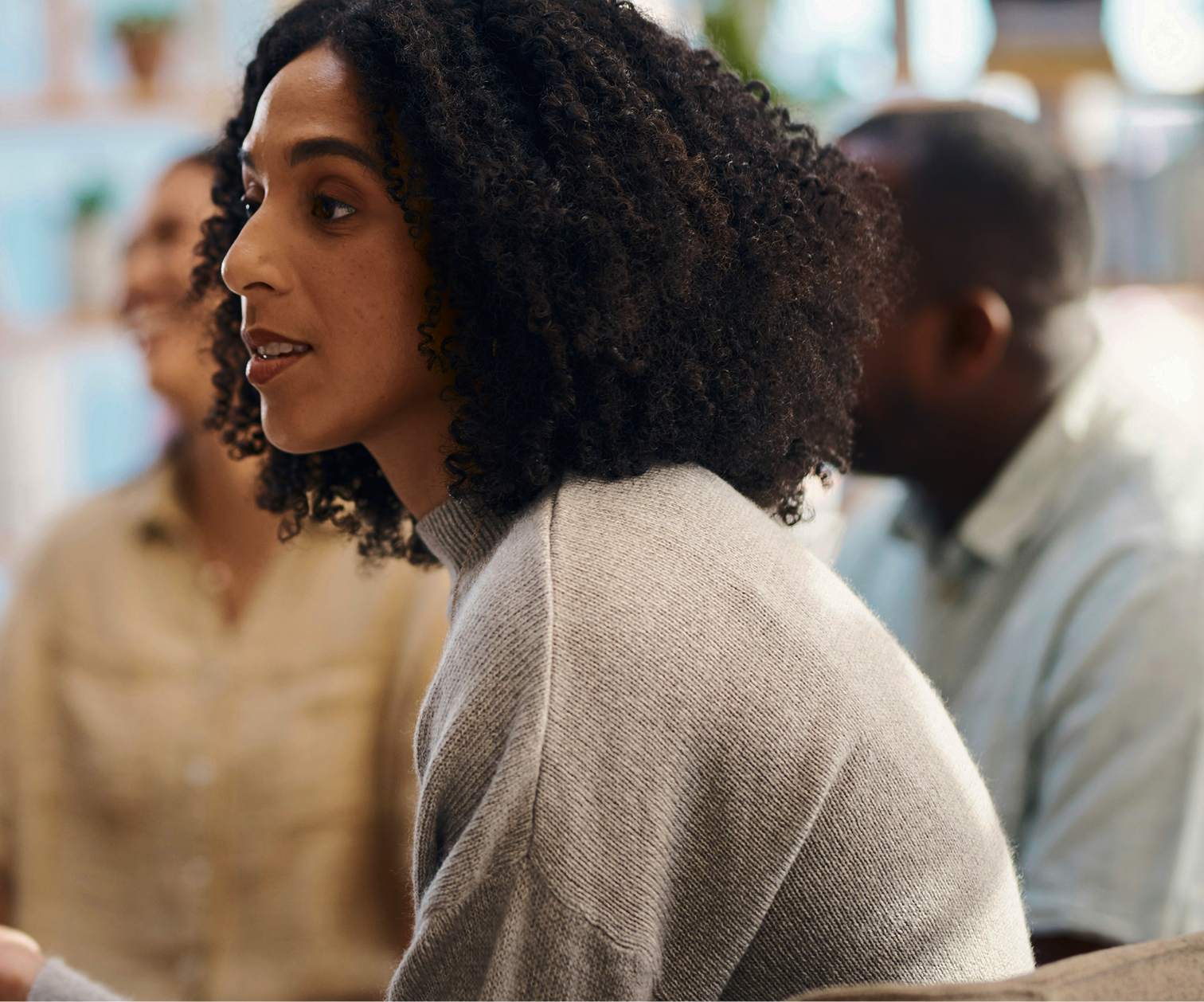 A leader speaking in profile during a group conversation, colleagues listening in the background