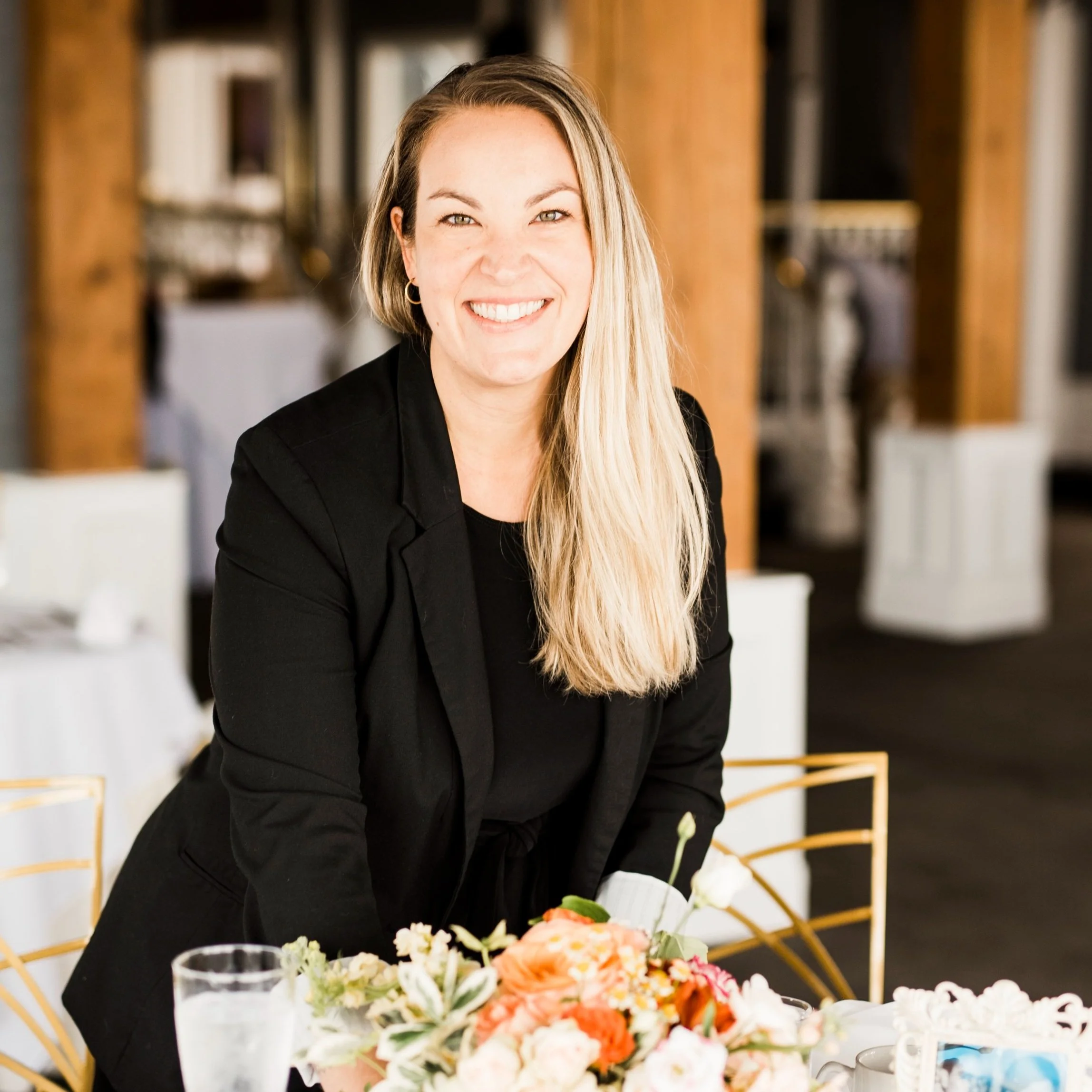 Brittney Bartling, founder of BLB Events, seated at a floral wedding table.