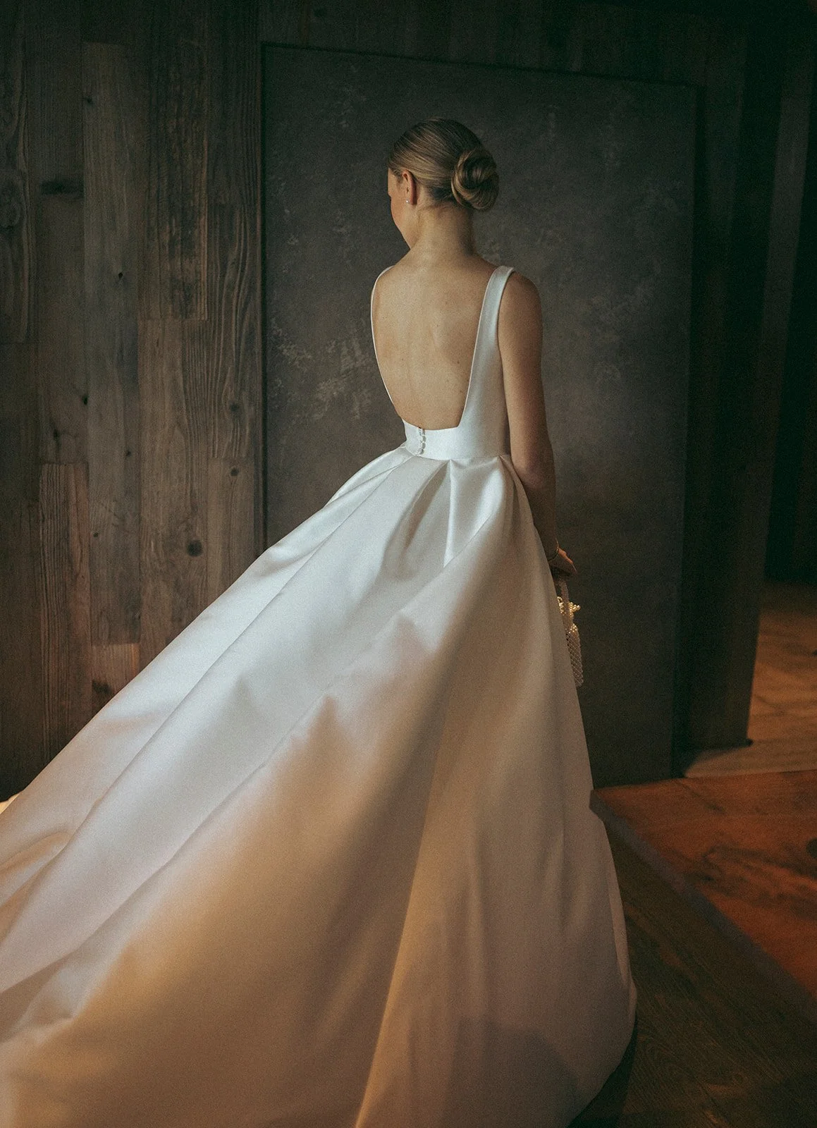 Bride seen from behind in a backless satin ball gown with a long train.