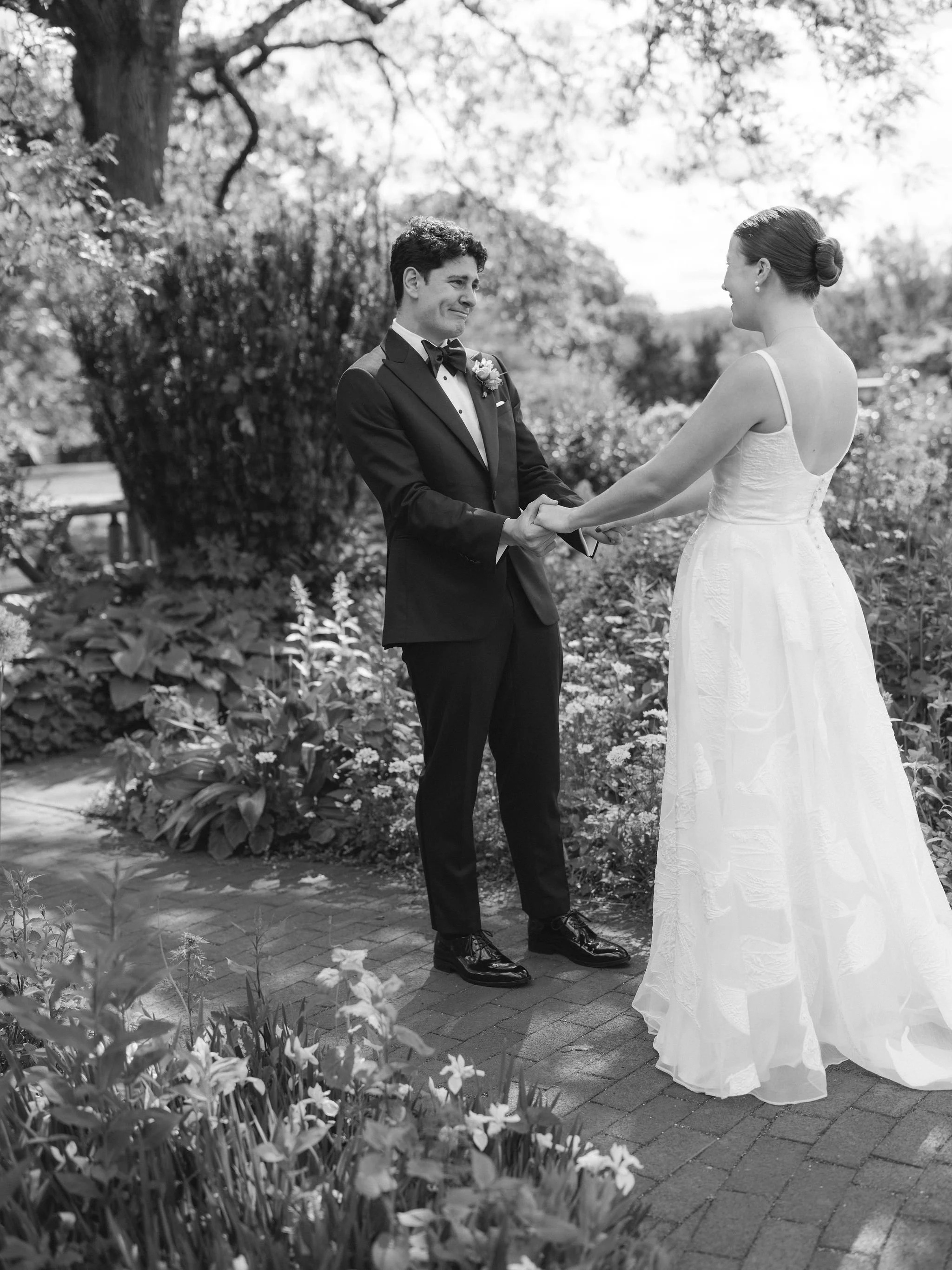 Black and white first look, couple holding hands in a garden.
