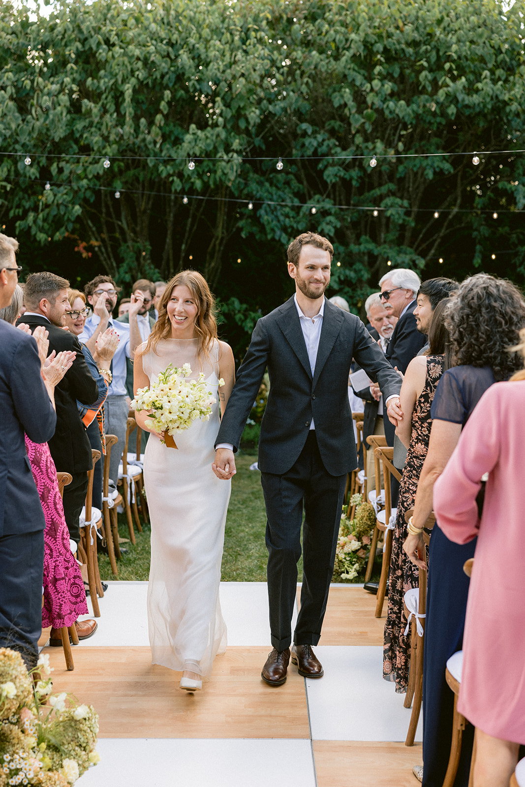 Recessional down an outdoor aisle as guests applaud.