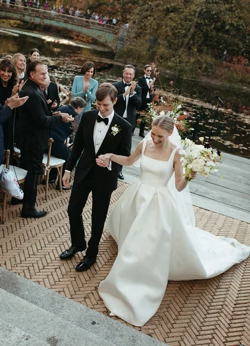 Couple walking down Central Park's Bow Bridge during their autumn recessional.