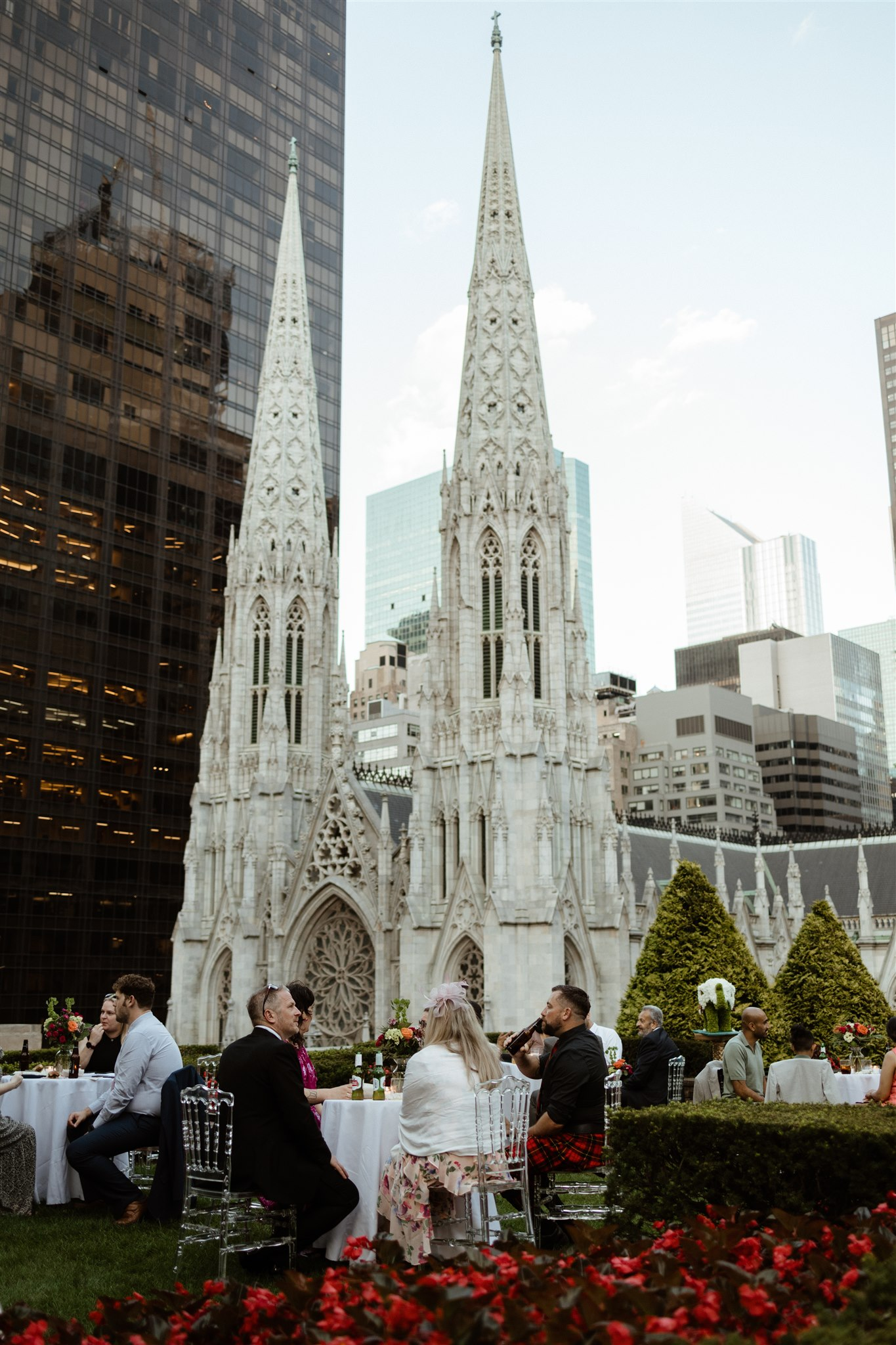 Rooftop wedding reception with the twin spires of St. Patrick's Cathedral behind the guest tables.