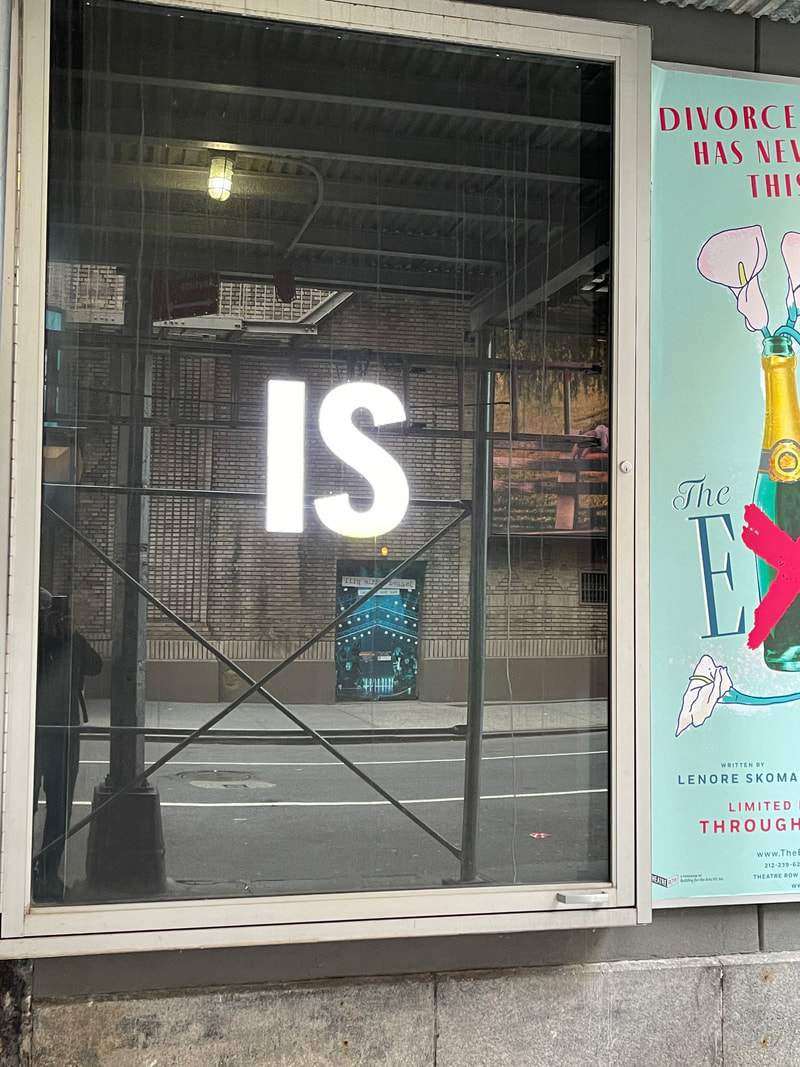 Illuminated letters in a bus shelter display case, NYC street, Broadway show poster alongside
