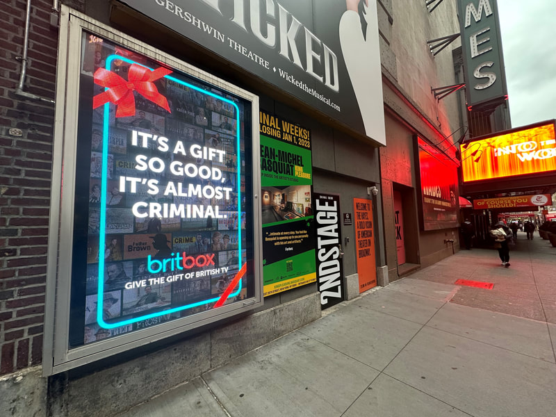BritBox 'It's a gift so good, it's almost criminal' poster in theater district display case, NYC