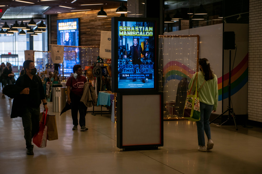 Sebastian Maniscalco digital kiosk screen in Brooklyn Center marketplace corridor