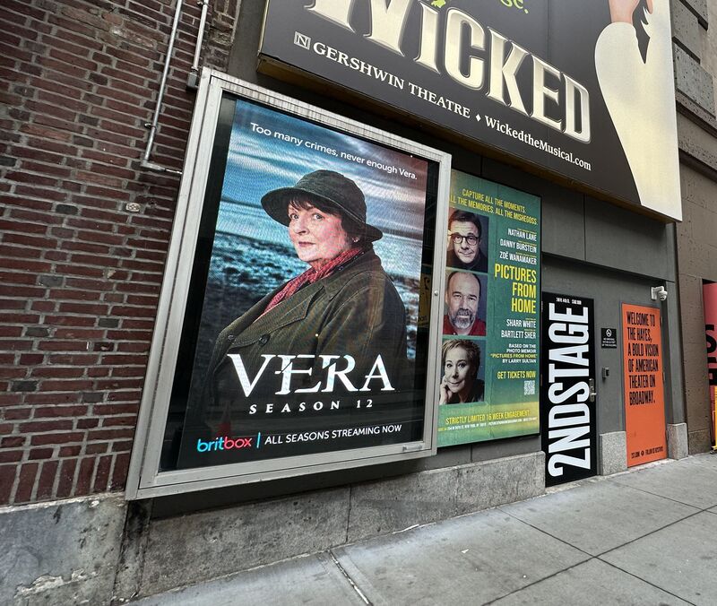 BritBox 'Vera Season 12' poster in illuminated display case on theater building, NYC