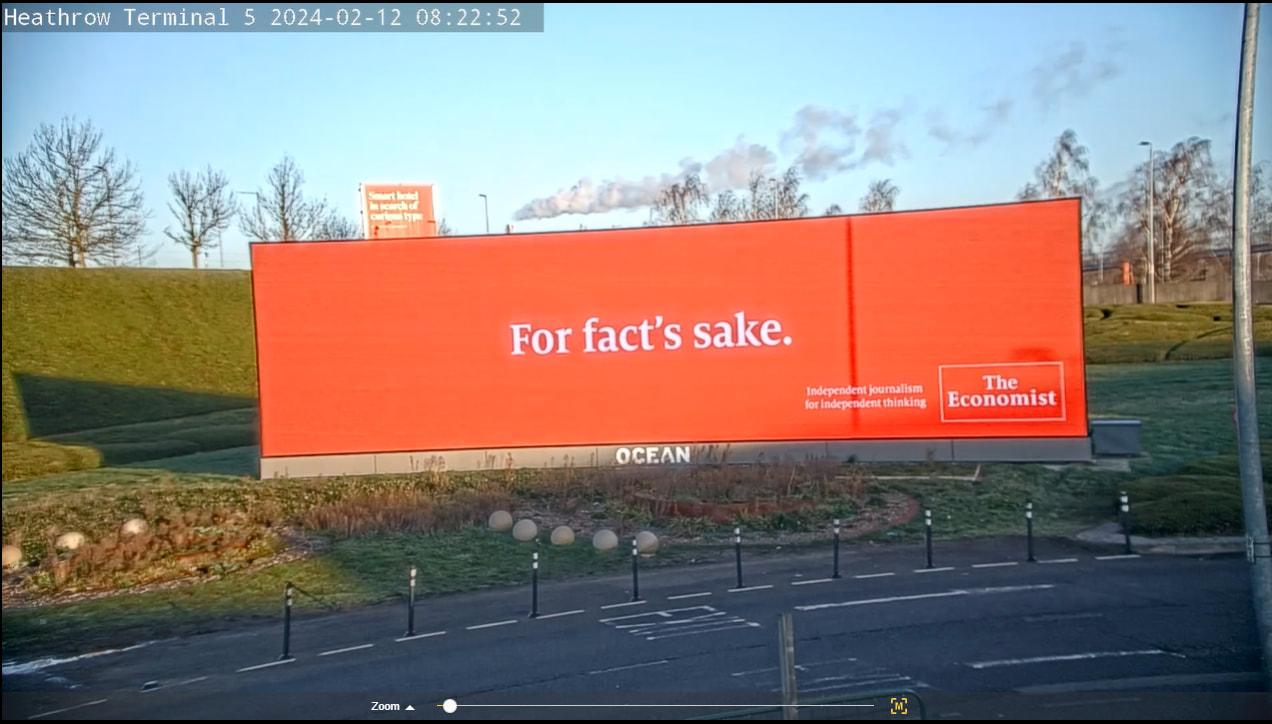 The Economist 'For fact's sake' billboard on a large outdoor screen at Heathrow Terminal 5