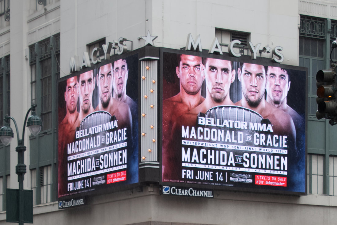 Bellator MMA Macdonald vs Gracie fight billboard on Macy's building corner, NYC