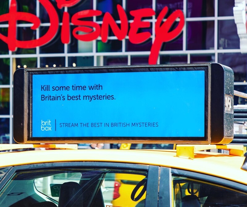 NYC taxi rooftop screen showing BritBox 'Kill some time with Britain's best mysteries' ad